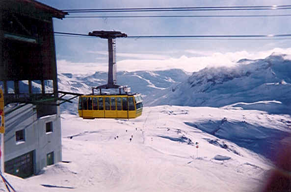Fantastisk godt billede på toppen af Rïfikopf (2363 m) med kabineliften Rüfikopf på vej ind med en flok skiløbere. Fremme foran os går henholdvis én rød pist (38a Steinmännle) og en blå piste (38 Monzabon-See) ned mod Zürs.