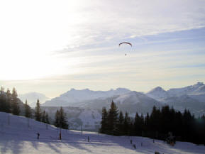 Paraglider hanging on the winds of the cliffs. View from apartment balcony.